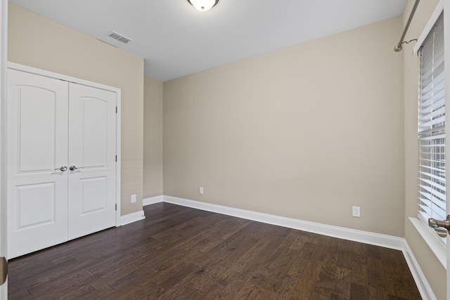 unfurnished bedroom with dark hardwood / wood-style flooring and a closet