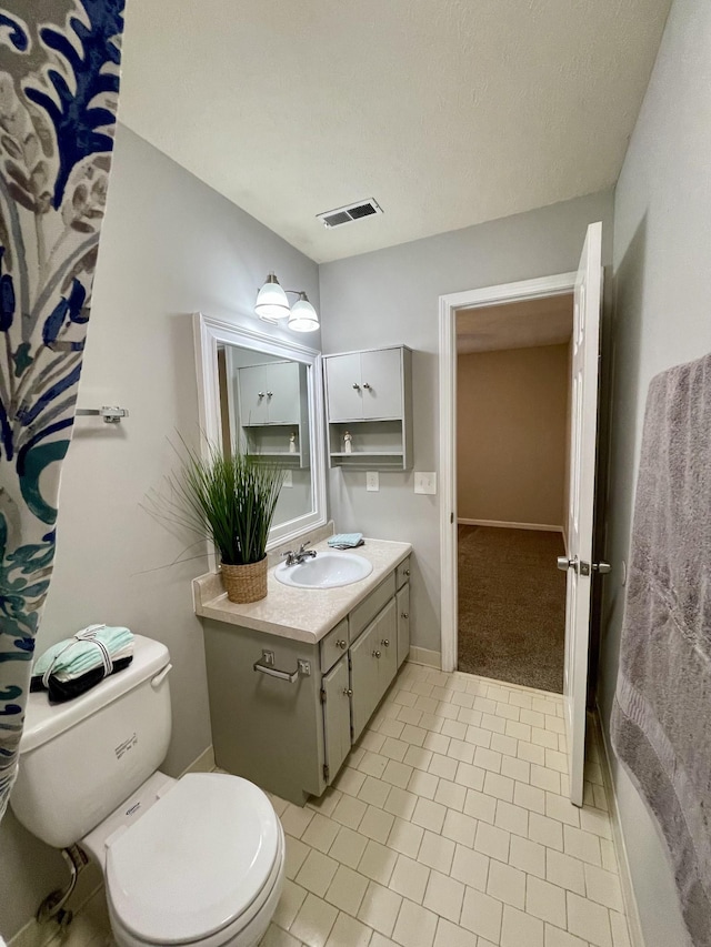 bathroom featuring tile patterned flooring, vanity, a textured ceiling, and toilet