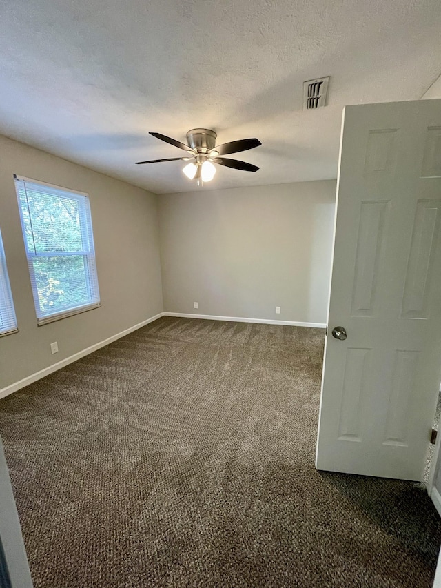 carpeted empty room with ceiling fan and a textured ceiling