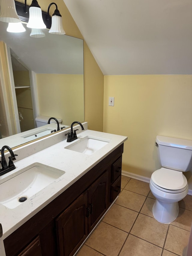 bathroom with lofted ceiling, tile patterned floors, toilet, and vanity