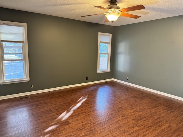 empty room with dark hardwood / wood-style flooring, ceiling fan, and a textured ceiling