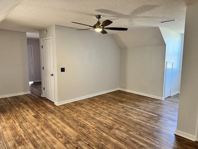 bonus room with a textured ceiling, vaulted ceiling, dark hardwood / wood-style floors, and ceiling fan