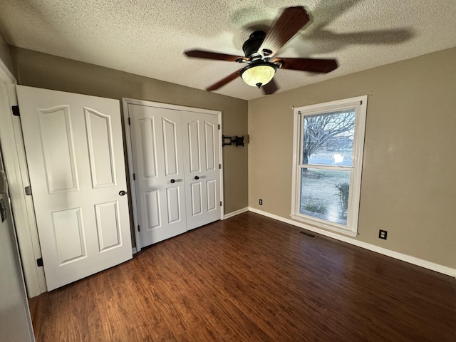 unfurnished bedroom featuring ceiling fan, dark wood-type flooring, a textured ceiling, and a closet