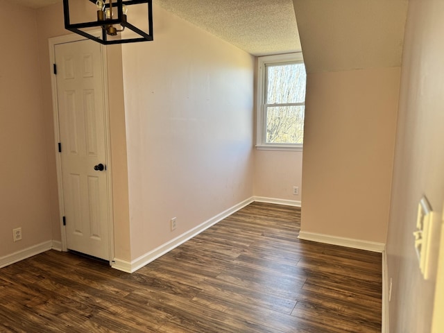 unfurnished room featuring dark hardwood / wood-style flooring, a notable chandelier, and a textured ceiling