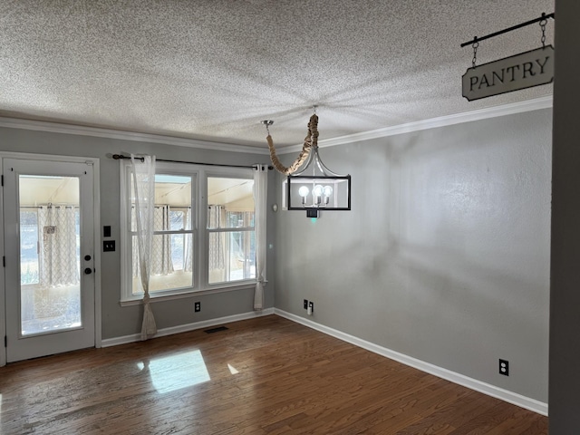 unfurnished dining area featuring ornamental molding, dark hardwood / wood-style floors, and a textured ceiling