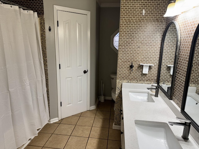 bathroom featuring vanity, brick wall, tile patterned floors, and toilet