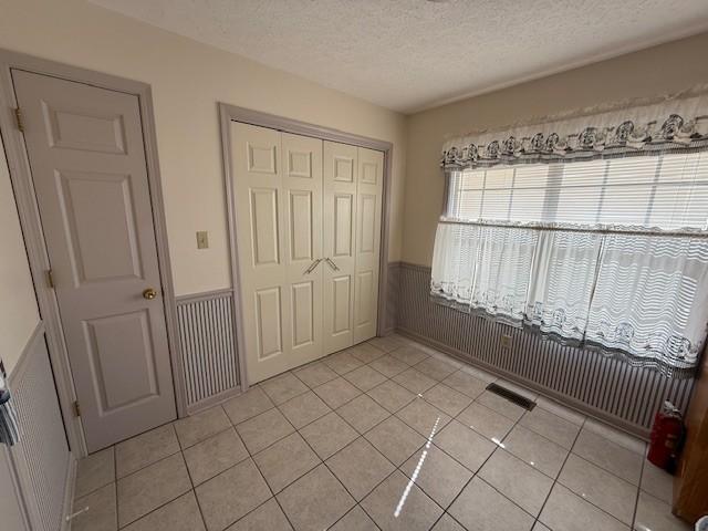 unfurnished bedroom featuring a closet, a textured ceiling, and light tile patterned floors