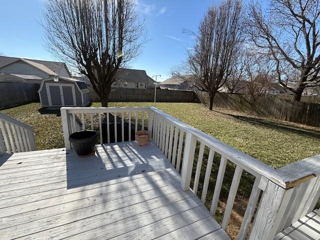 wooden terrace featuring a lawn and a storage unit