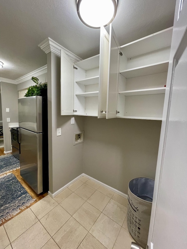 clothes washing area featuring crown molding, washer hookup, a textured ceiling, and light tile patterned floors