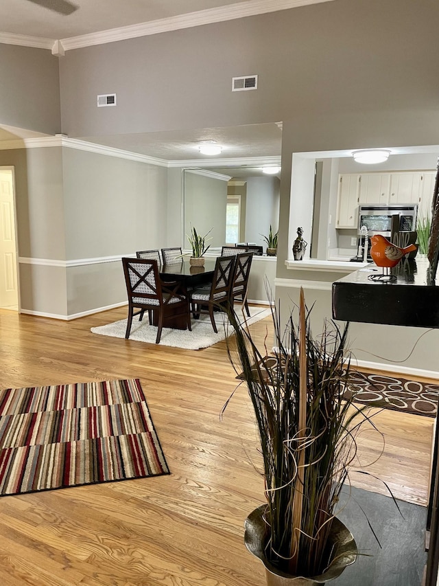 dining room with ornamental molding and light wood-type flooring