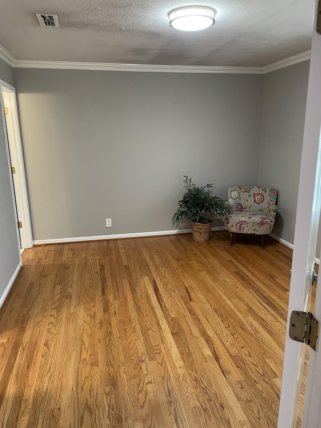 unfurnished room with crown molding, a textured ceiling, and light wood-type flooring