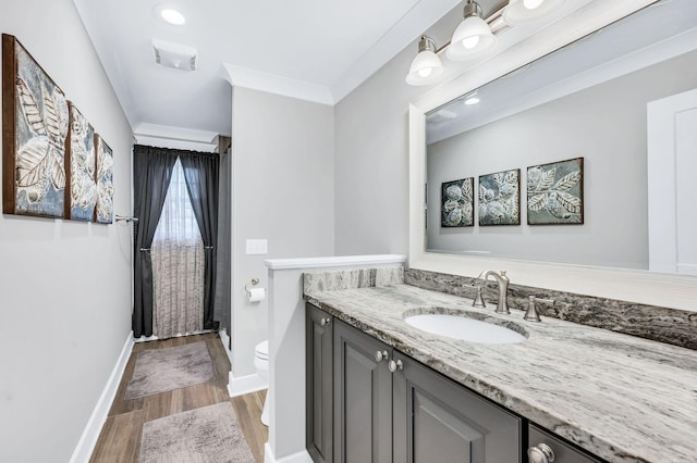 bathroom with wood-type flooring, vanity, crown molding, and toilet