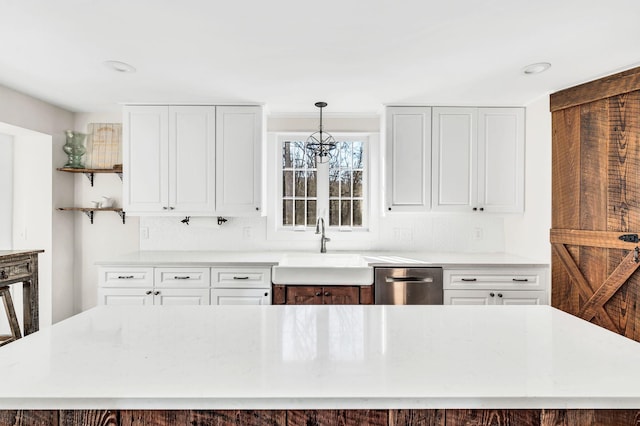 kitchen with sink, hanging light fixtures, stainless steel dishwasher, a kitchen island, and white cabinets