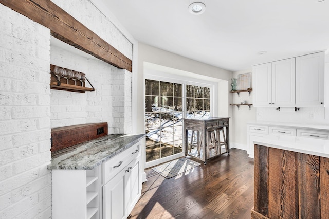 kitchen with light stone counters, dark hardwood / wood-style floors, and white cabinets