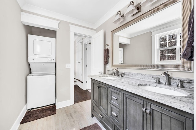 bathroom with hardwood / wood-style flooring, ornamental molding, stacked washer and clothes dryer, and vanity