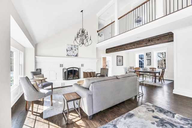 living room with a brick fireplace, dark hardwood / wood-style floors, high vaulted ceiling, and an inviting chandelier