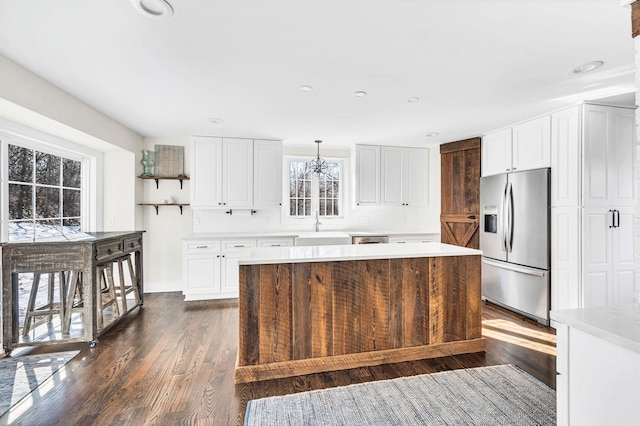 kitchen with white cabinetry, decorative light fixtures, stainless steel fridge, and a center island