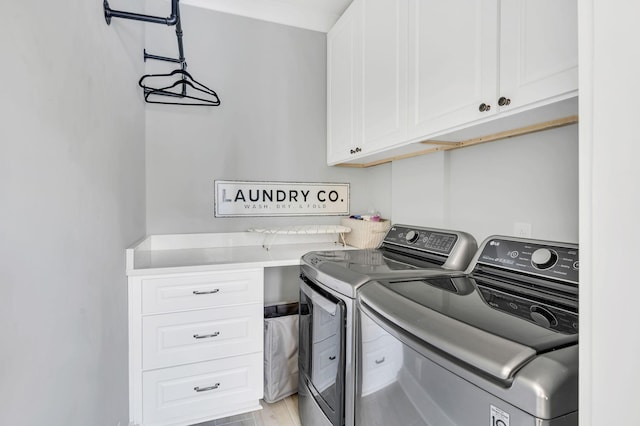 laundry area with cabinets, light wood-type flooring, and washer and clothes dryer