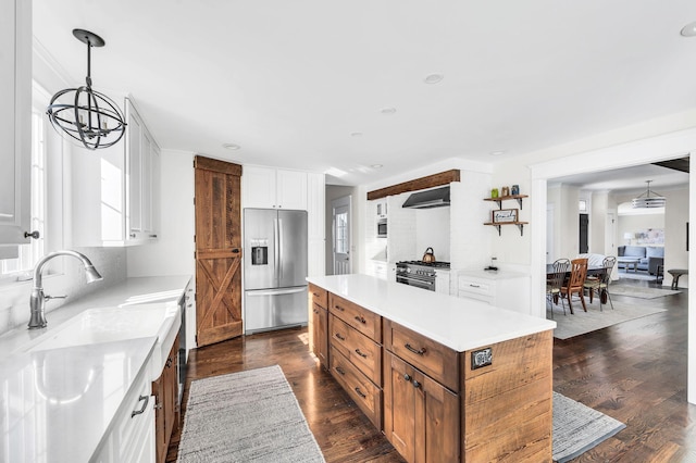 kitchen with sink, appliances with stainless steel finishes, a kitchen island, pendant lighting, and white cabinets