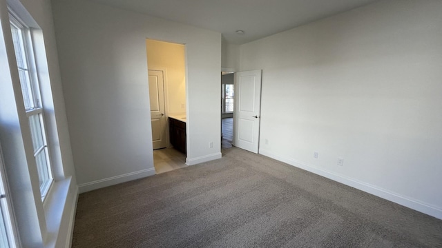 unfurnished bedroom featuring connected bathroom and light colored carpet