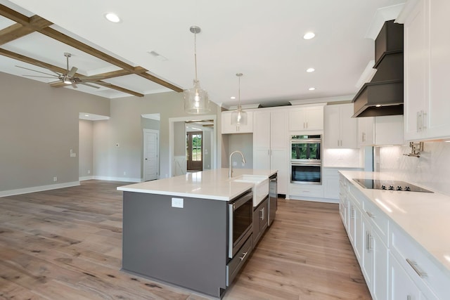 kitchen featuring tasteful backsplash, stainless steel appliances, an island with sink, and white cabinets