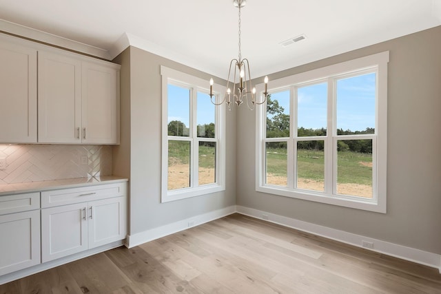 unfurnished dining area with a notable chandelier and light wood-type flooring