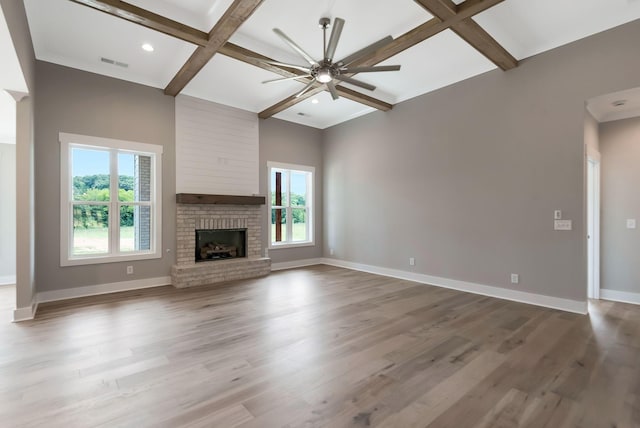 unfurnished living room featuring coffered ceiling, hardwood / wood-style floors, a fireplace, and ceiling fan