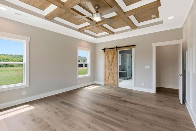 spare room with coffered ceiling, hardwood / wood-style flooring, a barn door, and beamed ceiling