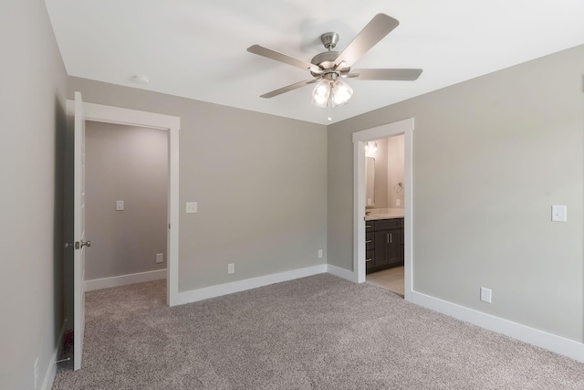 unfurnished bedroom featuring ensuite bathroom, light colored carpet, and ceiling fan