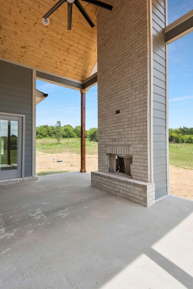 view of patio with an outdoor brick fireplace and ceiling fan