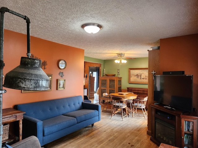 living room with ceiling fan, light hardwood / wood-style floors, and a textured ceiling