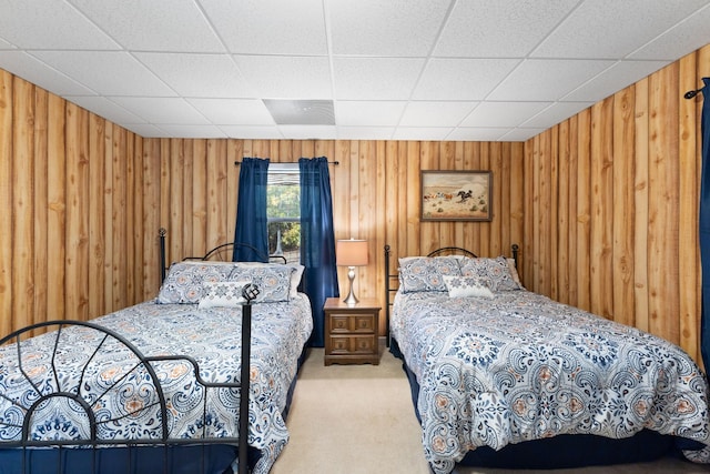 bedroom with carpet flooring, a paneled ceiling, and wood walls