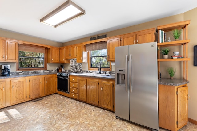 kitchen with electric range oven, sink, and stainless steel fridge