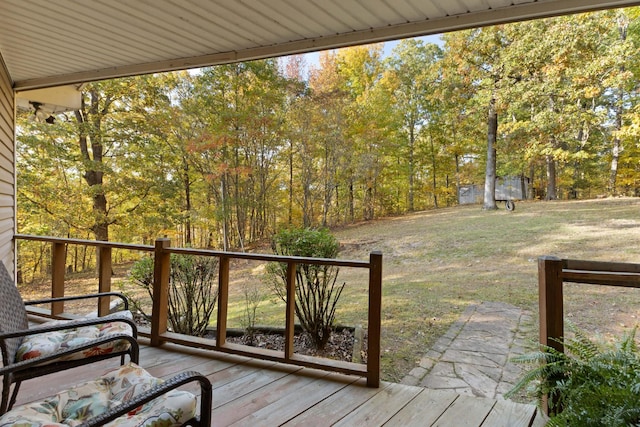 wooden deck featuring a yard and a storage unit