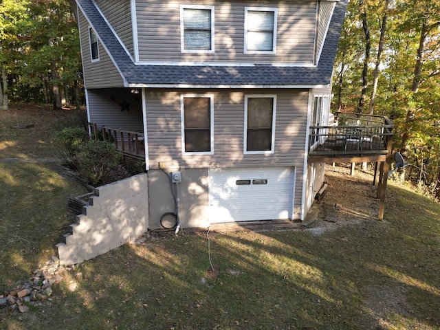 rear view of house with a garage, a wooden deck, and a yard