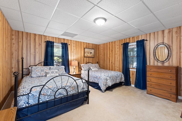 carpeted bedroom featuring a paneled ceiling and wooden walls