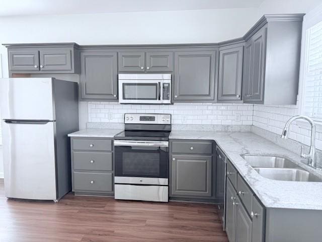 kitchen featuring sink, gray cabinets, appliances with stainless steel finishes, light stone countertops, and dark hardwood / wood-style flooring