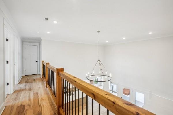 corridor featuring an inviting chandelier and light hardwood / wood-style flooring