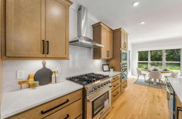 kitchen with decorative backsplash, stainless steel appliances, wall chimney exhaust hood, and light wood-type flooring