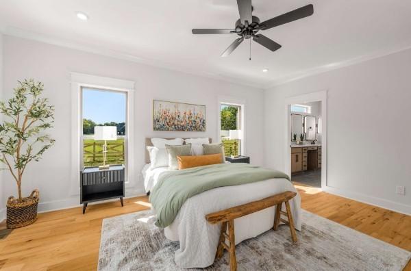 bedroom with connected bathroom, hardwood / wood-style flooring, ornamental molding, and ceiling fan