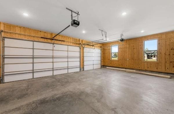 garage featuring a garage door opener, wooden walls, and baseboard heating