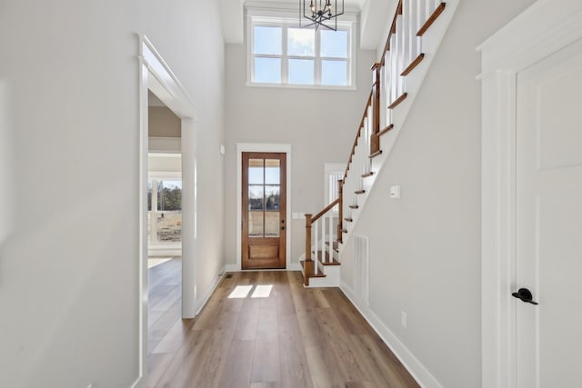 foyer entrance with a high ceiling, an inviting chandelier, and light hardwood / wood-style floors