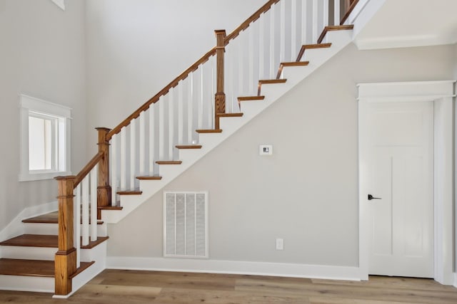 stairway featuring a towering ceiling and wood-type flooring