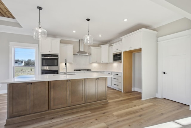 kitchen with built in microwave, an island with sink, white cabinets, stainless steel double oven, and wall chimney range hood