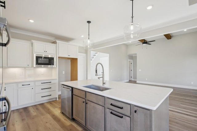 kitchen featuring sink, dishwasher, white cabinetry, an island with sink, and built in microwave