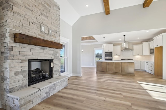 kitchen with pendant lighting, wall chimney exhaust hood, a spacious island, white cabinets, and stainless steel double oven