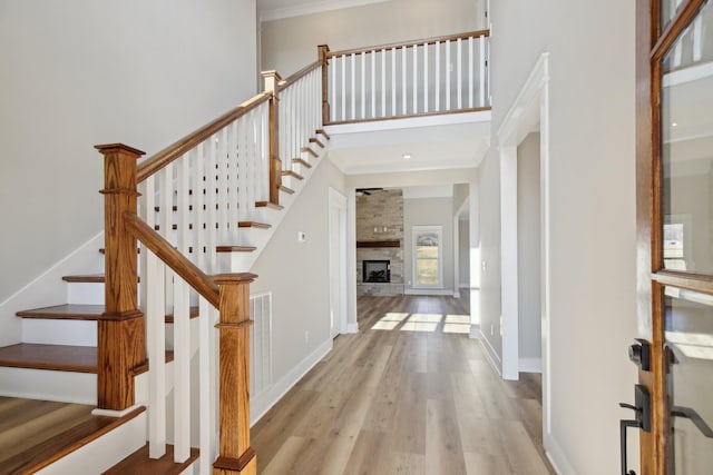 foyer entrance featuring a high ceiling, a large fireplace, and light wood-type flooring