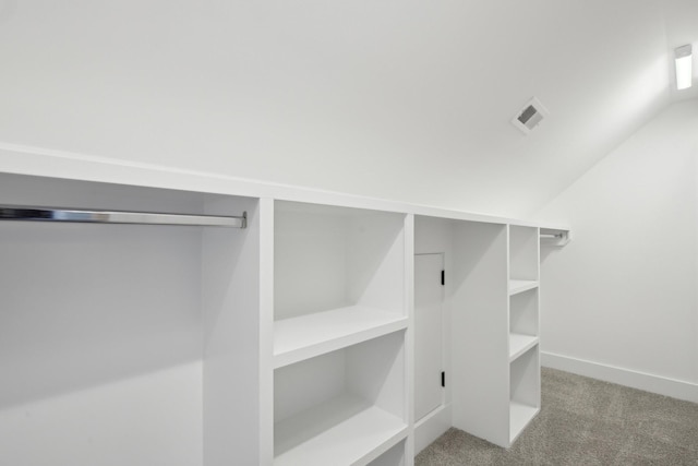 spacious closet with lofted ceiling and light colored carpet