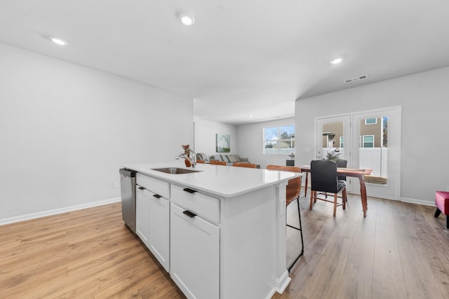 kitchen featuring sink, light hardwood / wood-style flooring, dishwasher, an island with sink, and white cabinets