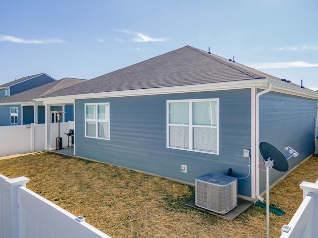 back of house with a lawn and central air condition unit